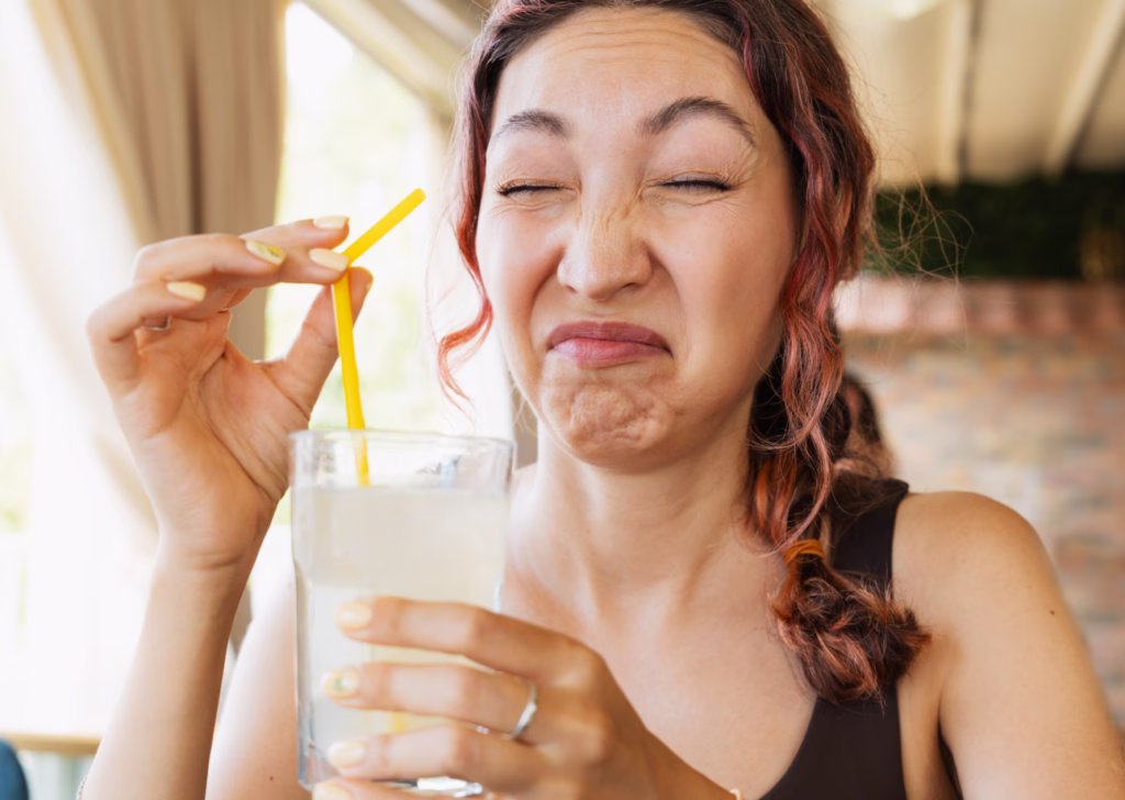 Woman reacting to bad-smelling well water in a glass